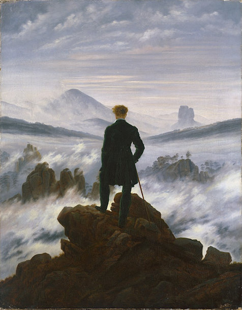 Man standing on mountaintop looking at other peaks in front of him