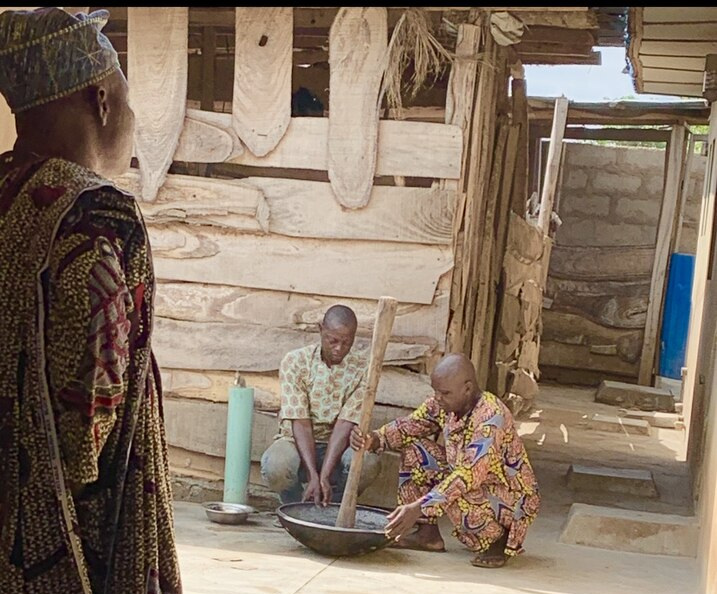 Two African men in traditional clothing mixing something in a large bowl