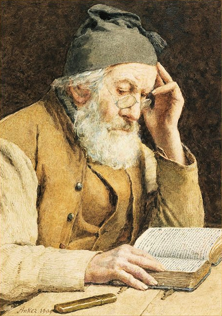 old man sitting at a table reading the Bible